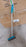 Long-handle scrub brush for cleaning floors and tiles, featuring stiff bristles.